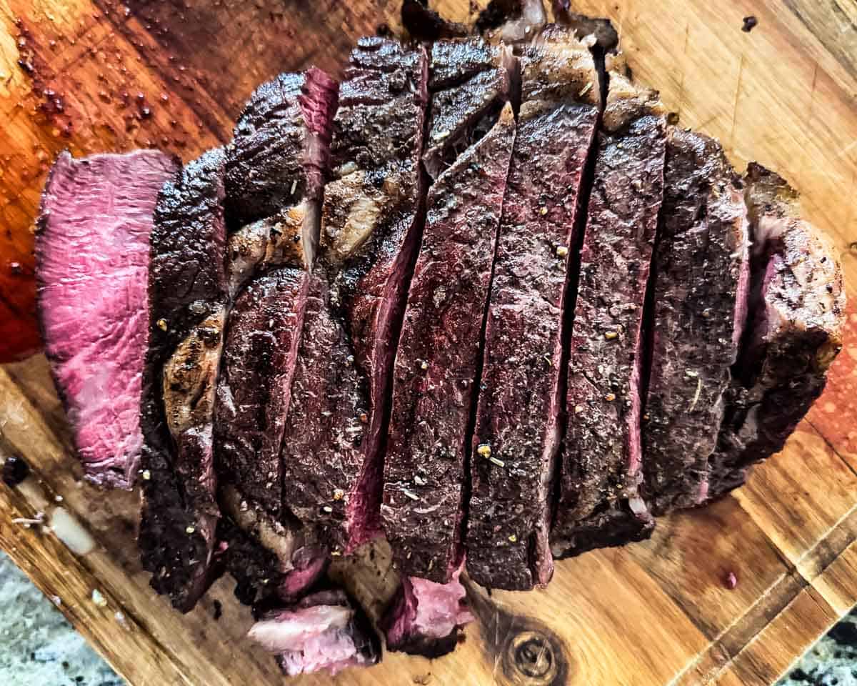 Reverse-seared smoked tomahawk steak sliced to show the juicy pink center.