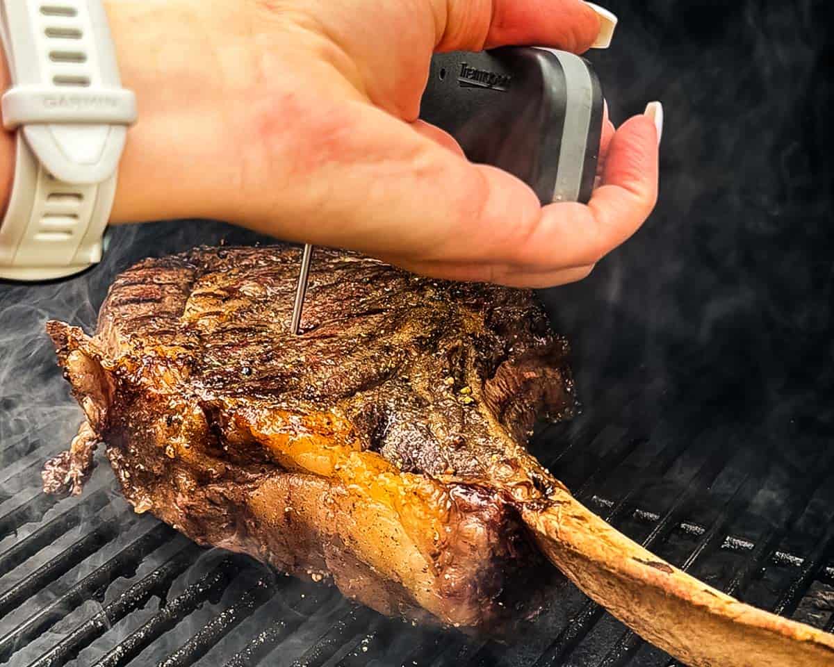 Checking the internal temperature of a tomahawk steak during the reverse sear.