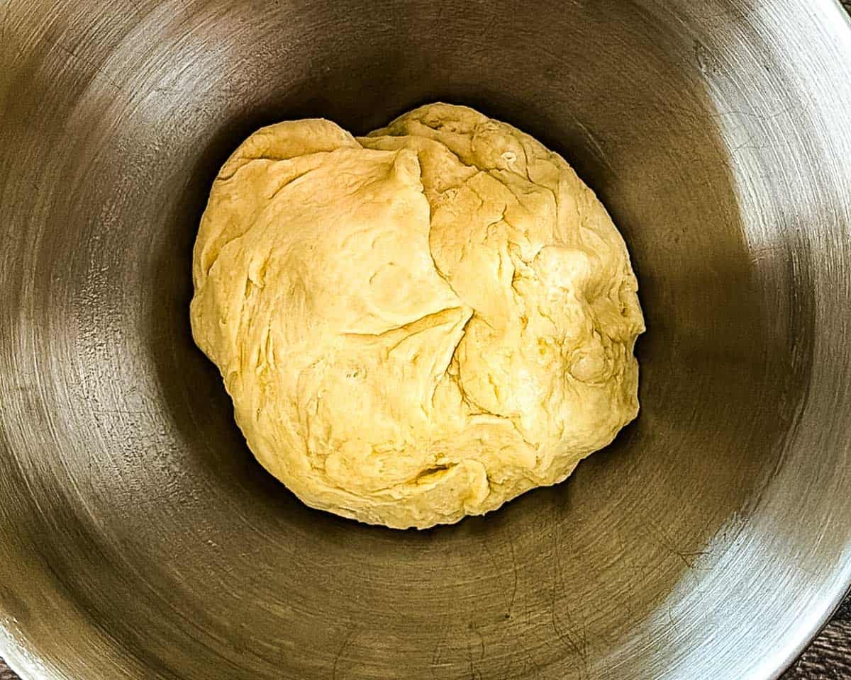 Soft sourdough discard cinnamon bun dough in a mixing bowl.