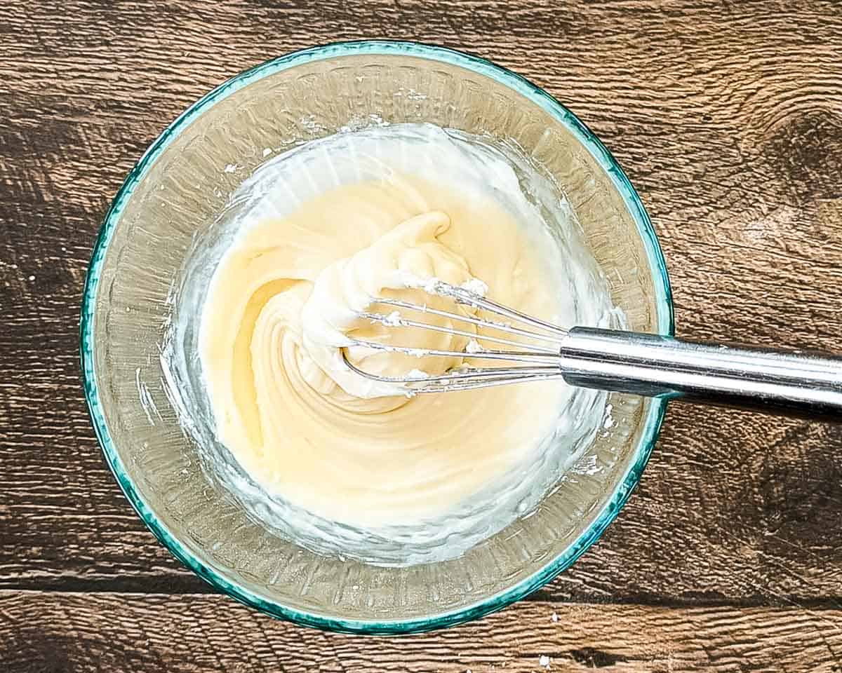 Whisking the powdered sugar, cream, and vanilla together in a bowl for the icing.