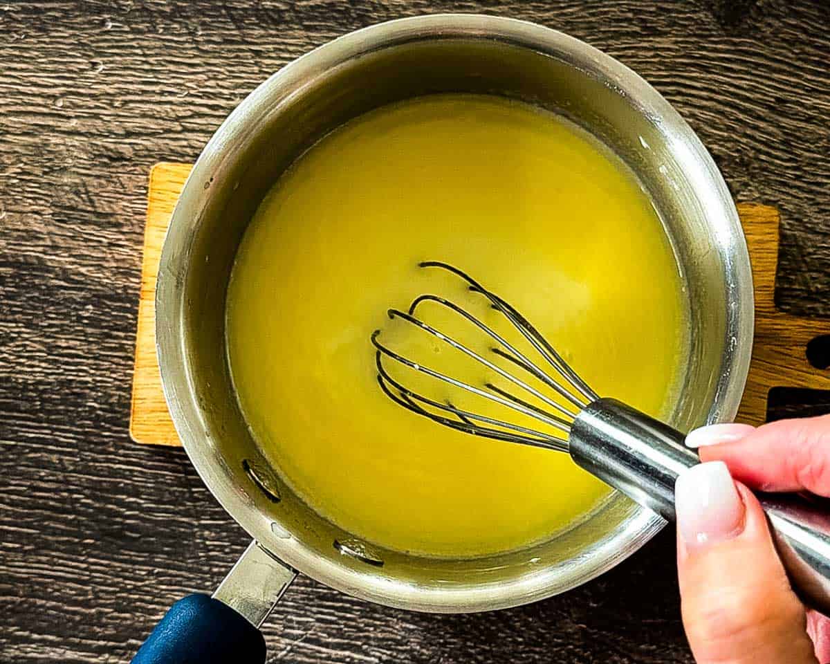Whisking milk and melted butter in a saucepan for cinnamon bun dough.
