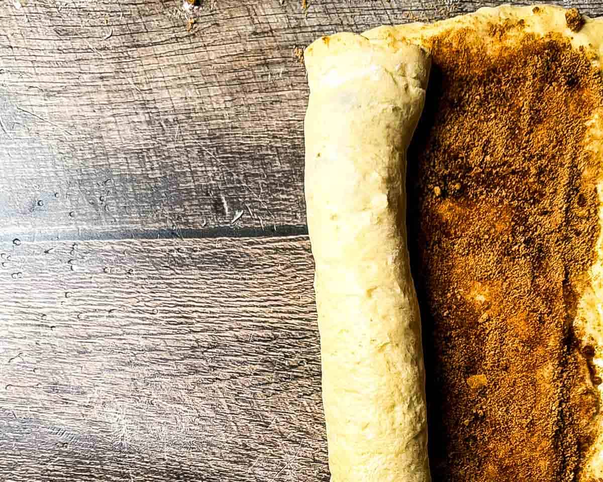 Cinnamon sugar covered dough being rolled into a log.