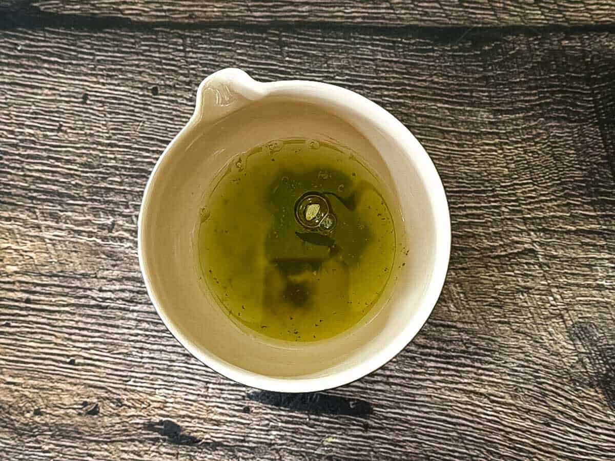 Sifted matcha powder combined with water in a small bowl before whisking.