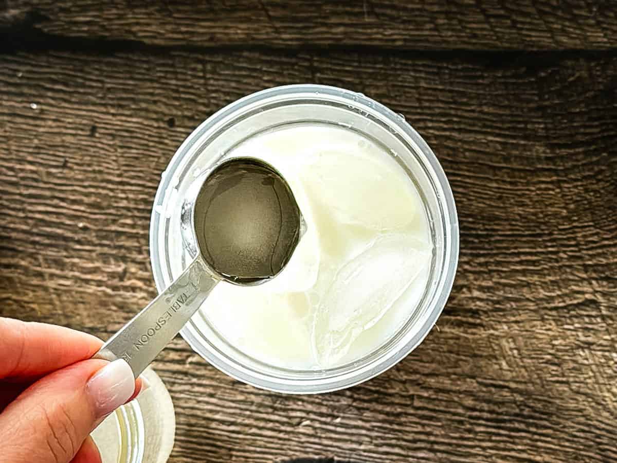 Adding simple syrup to a homemade iced matcha latte.