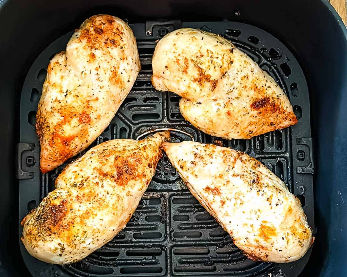 Cooked air fryer chicken breasts golden brown in the air fryer basket.