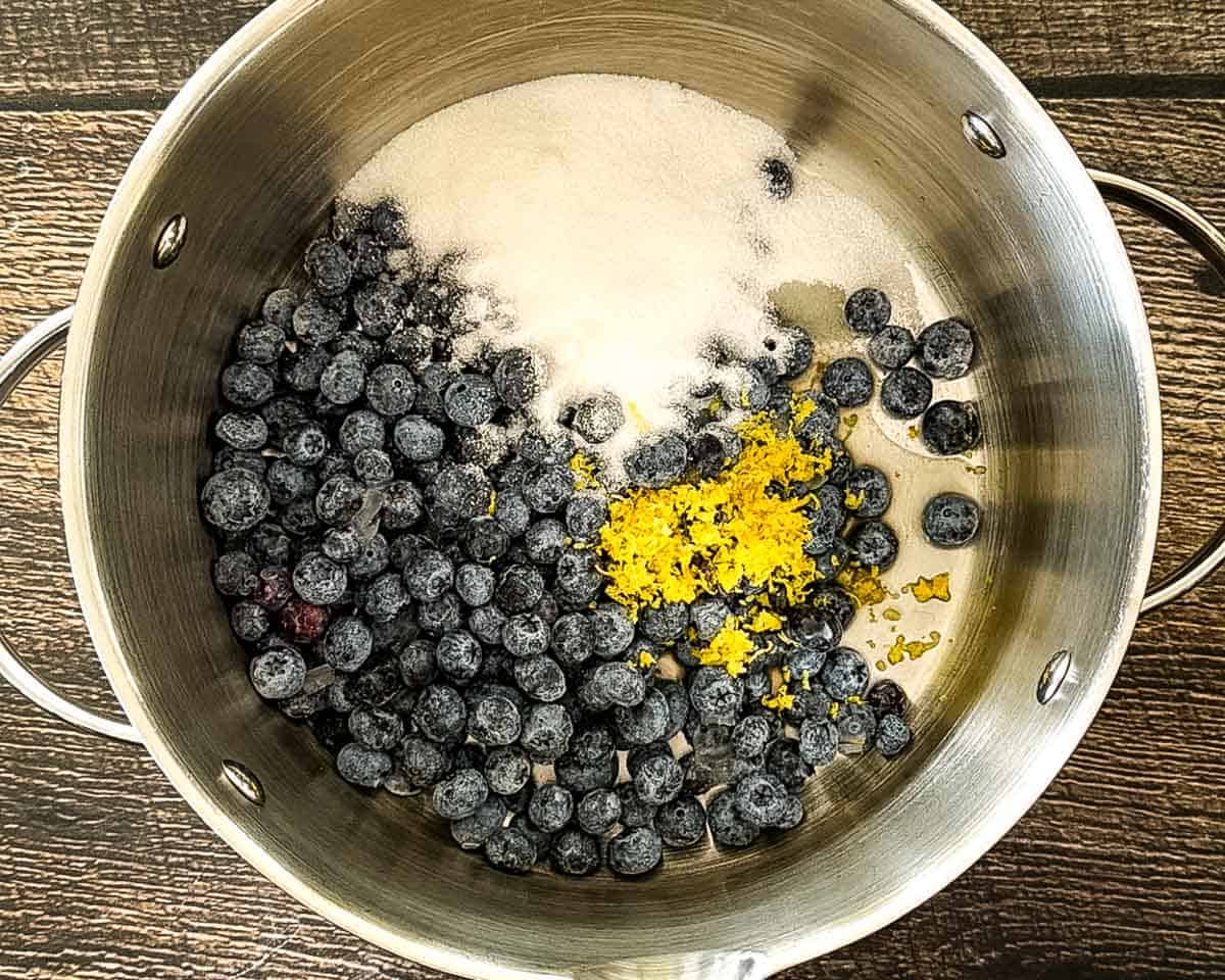 Blueberries, sugar, lemon juice, and lemon zest combined in a saucepan.
