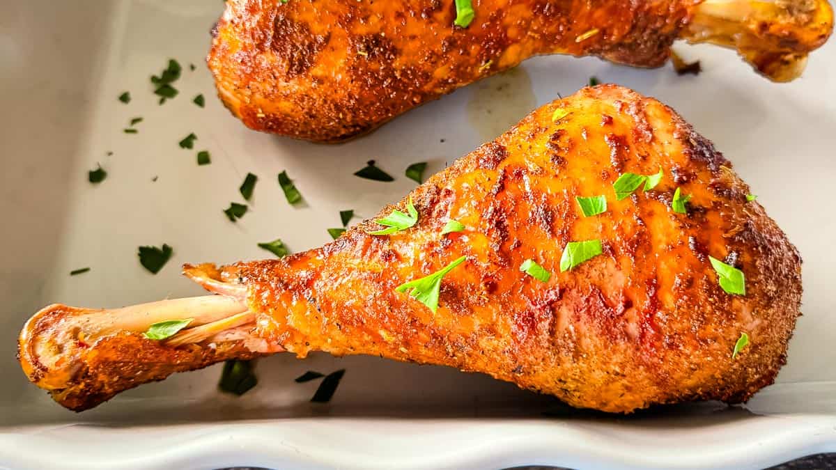 Smoked turkey legs with browned crispy skin garnished with fresh parsley.