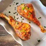 Smoked turkey legs smoked on a pellet grill with browned, seasoned skin and fresh parsley.