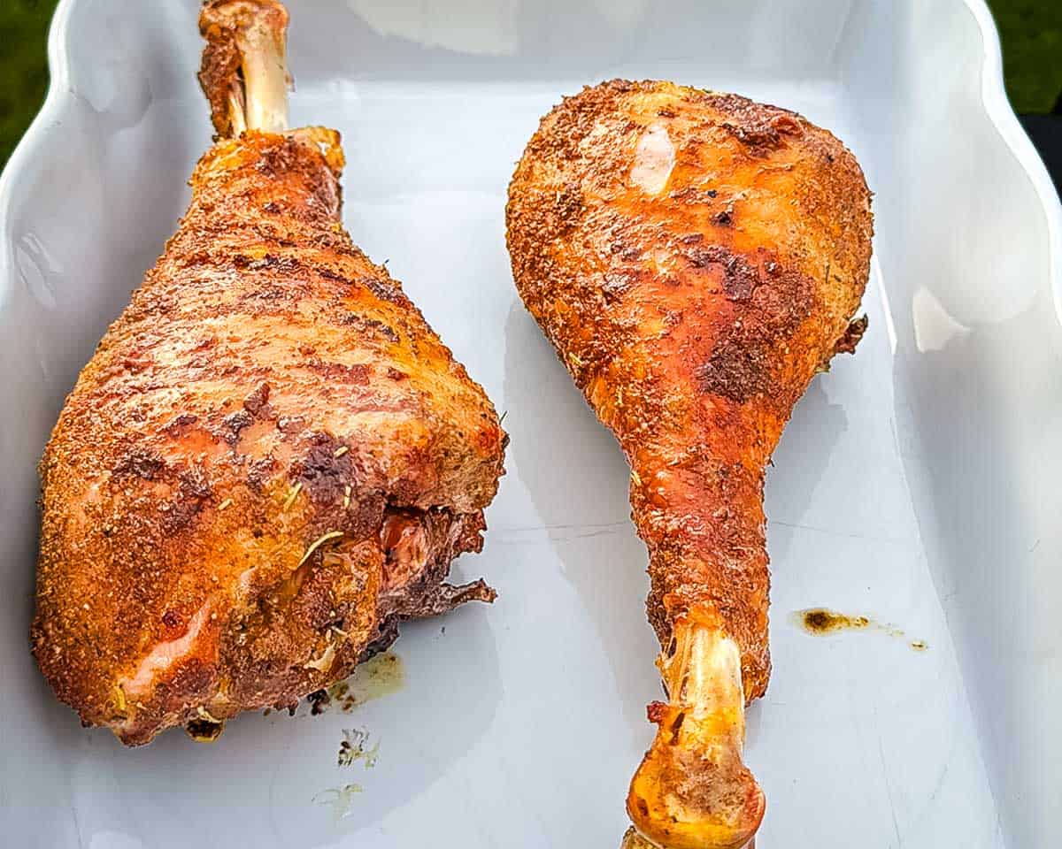 The turkey drumsticks resting in a white platter before serving.