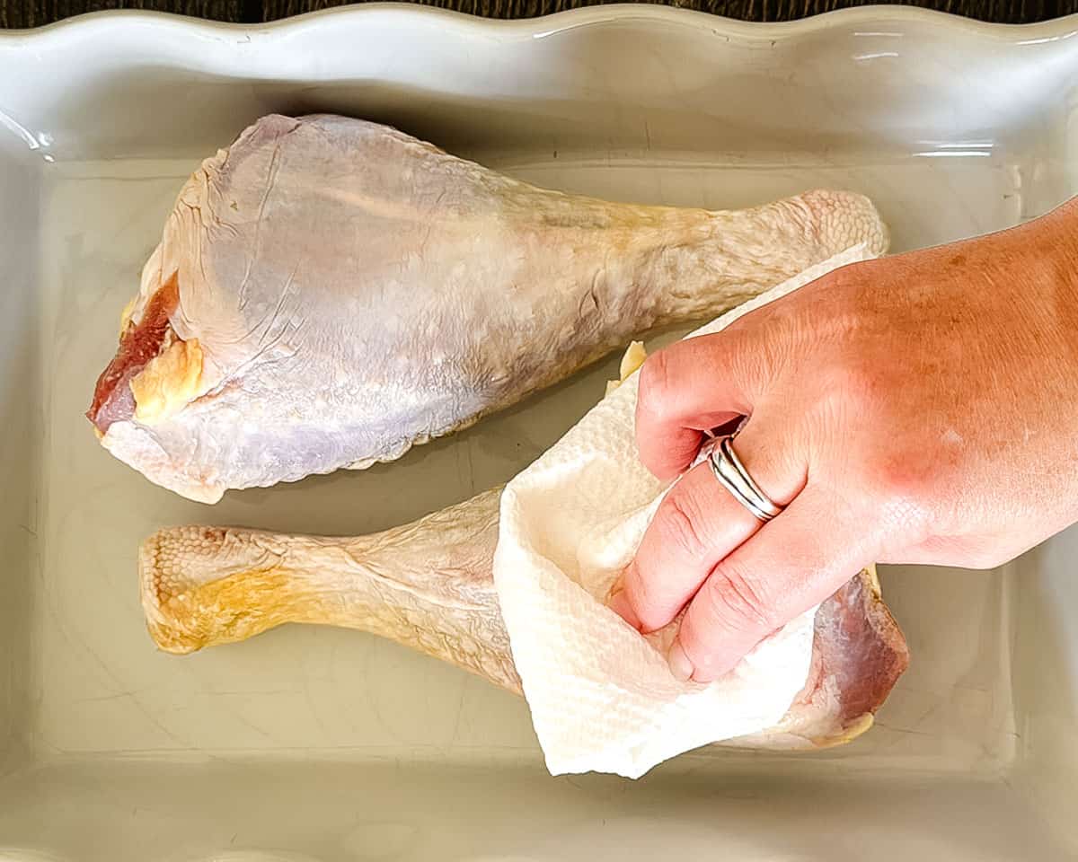 Patting turkey legs dry with a paper towel before seasoning.