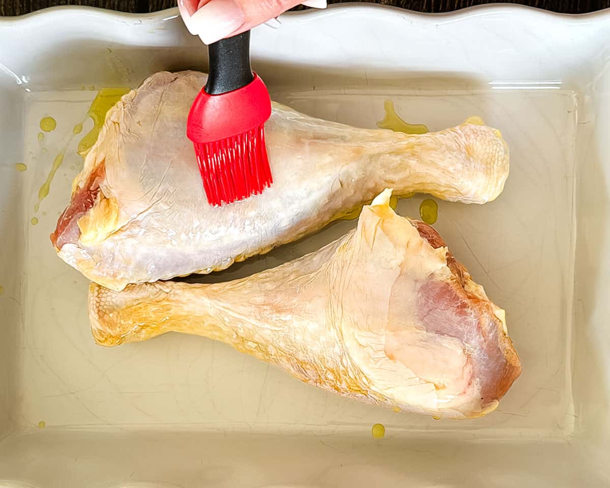 Brushing olive oil over turkey legs before adding the seasoning.