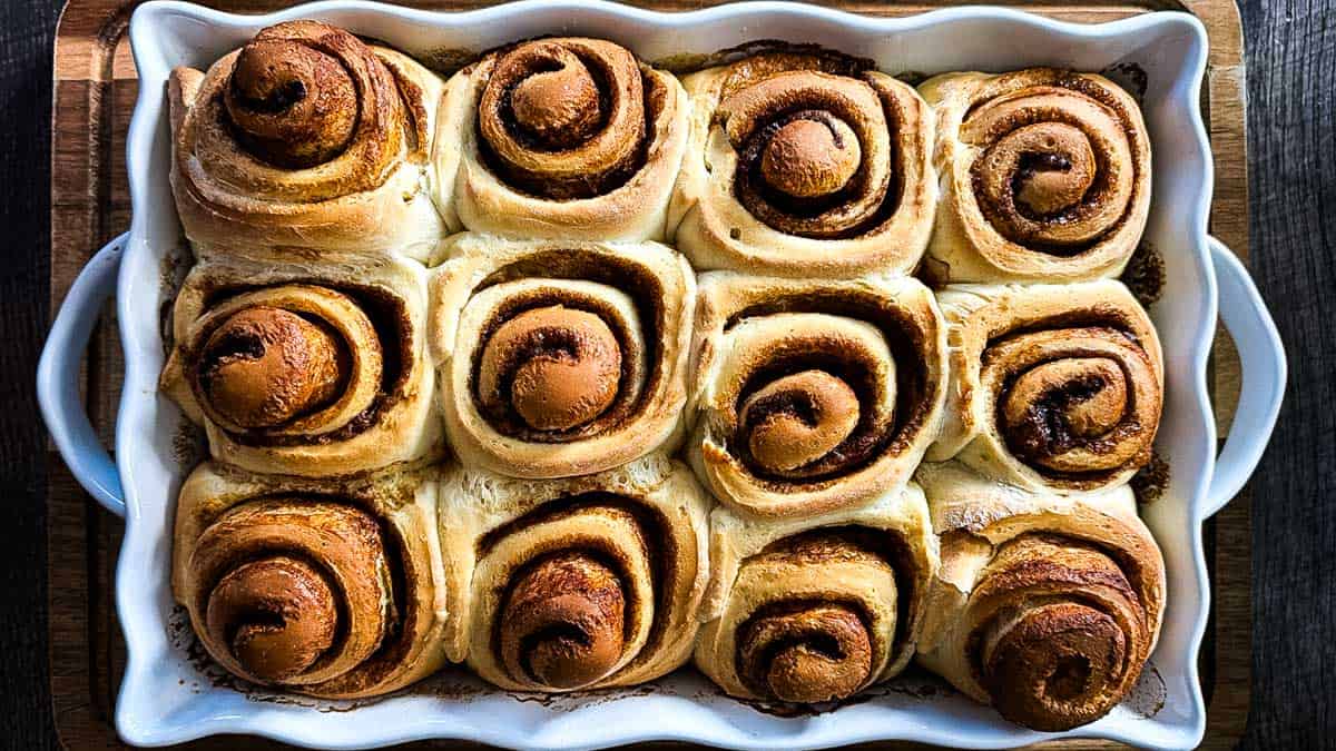 Cinnamon buns in a baking dish after the baking time is over, showing the golden brown tops.