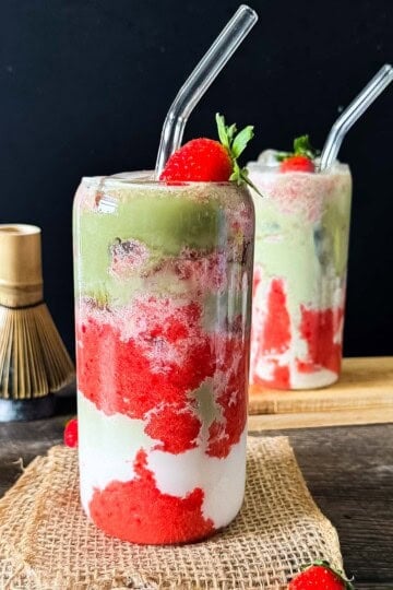 Iced strawberry matcha latte layered with strawberry puree, milk, and matcha.