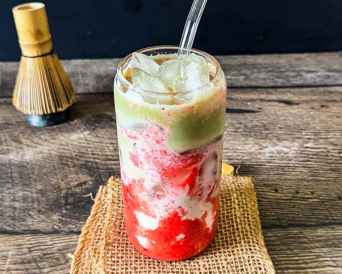 Strawberry matcha latte layered with fresh strawberry puree, milk, and green matcha in a clear glass.