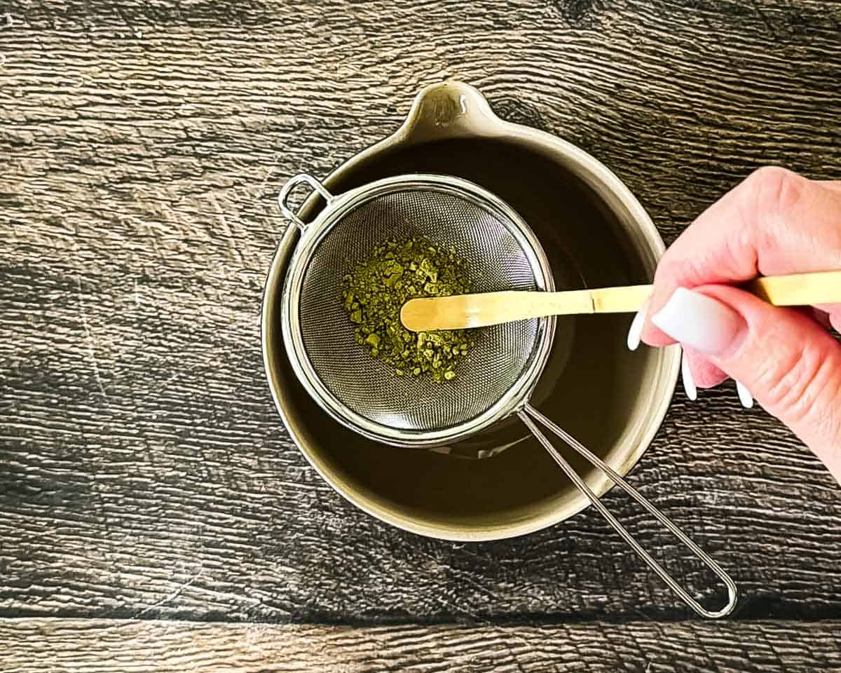 Matcha powder being sifted into a bowl to remove clumps.