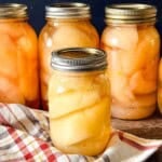 Pear halves packed in light syrup in glass canning jars.