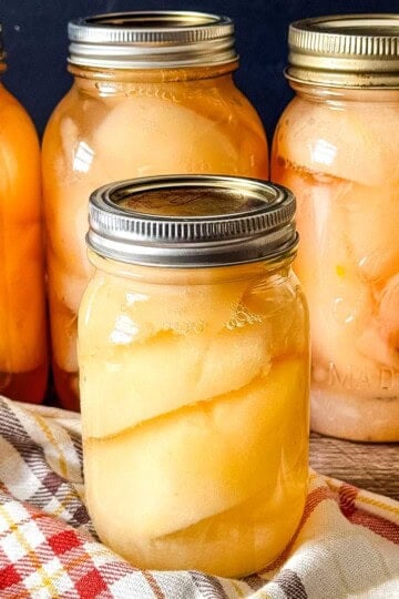 Pear halves packed in light syrup in glass canning jars.