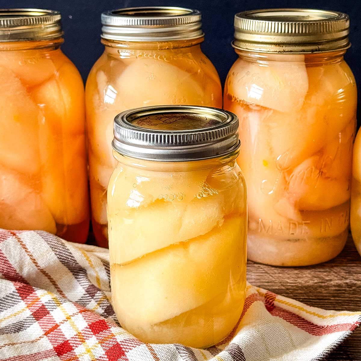 Pear halves packed in light syrup in glass canning jars.