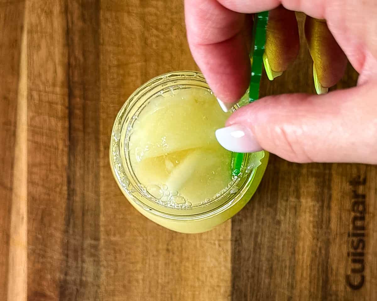 Removing air bubbles from a jar of pears packed in syrup.