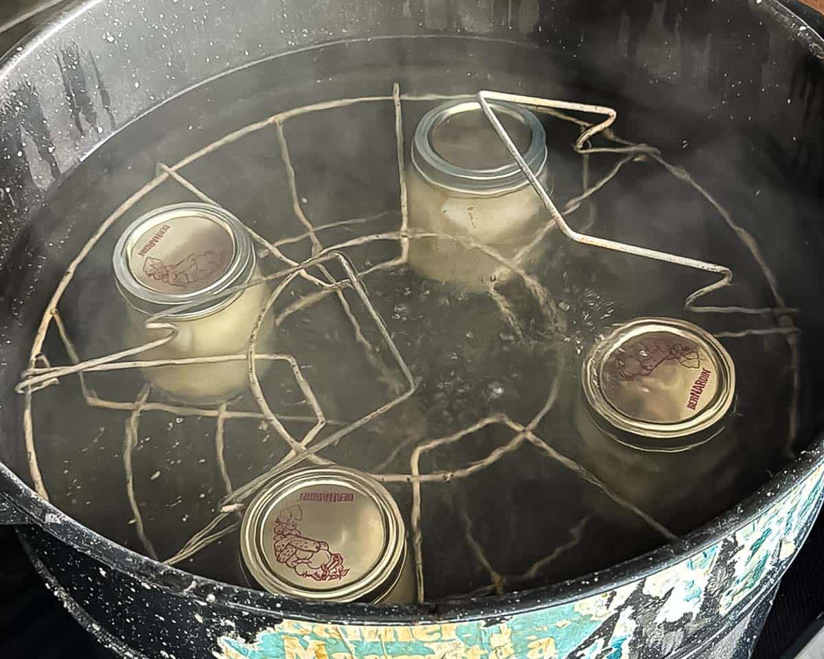 Jars of canned pears in a boiling-water bath canner for processing.