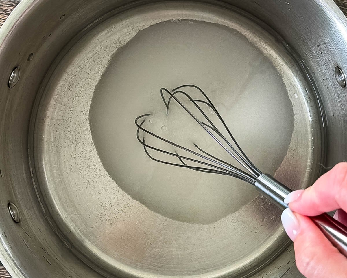 Whisking sugar and water together to make light syrup for canned pears.