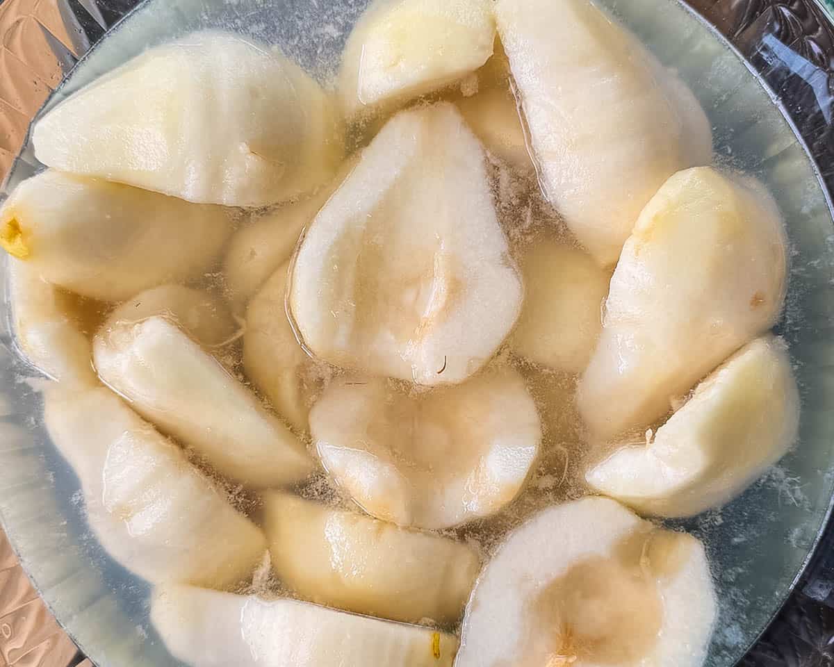 Peeled pear halves soaking in a browning solution before canning.
