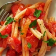 Casarecce pasta all Peperonata on a white dinner plate with a fork.