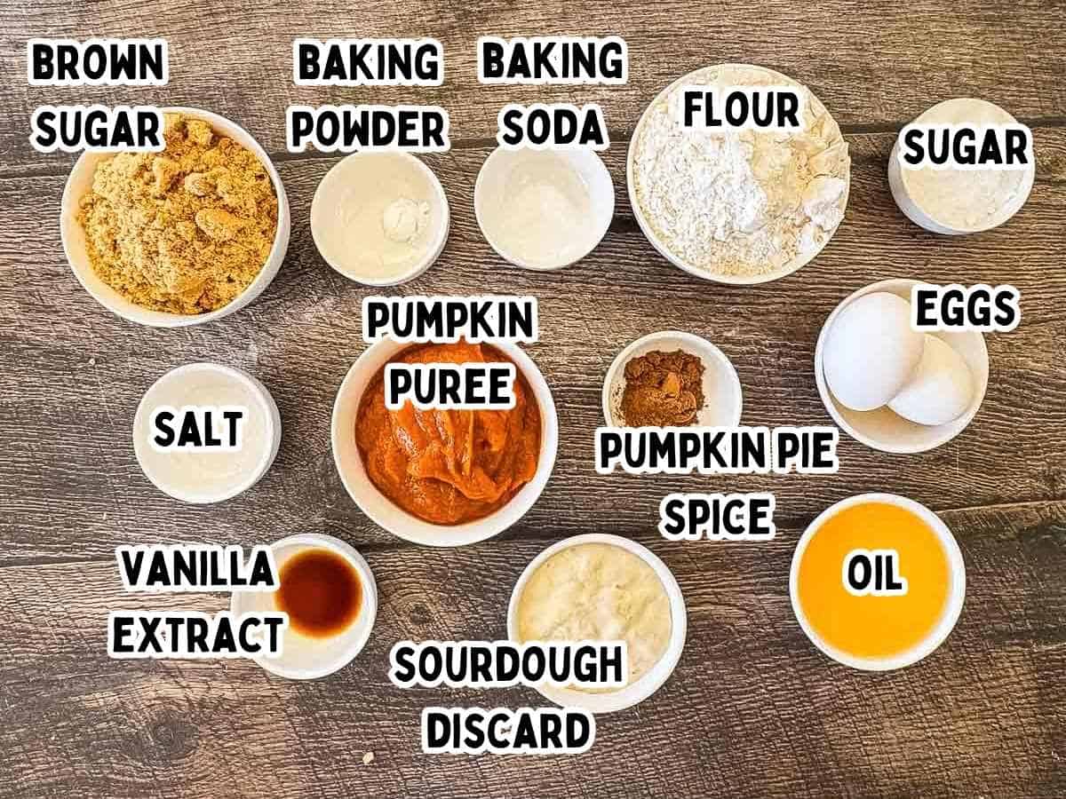 Ingredients for sourdough discard pumpkin bread, including flour, pumpkin puree, sourdough discard, sugars, eggs, oil, spices, and baking essentials.