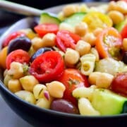 Mediterranean chickpea salad in a black bowl with a fork.
