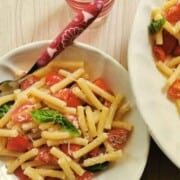 Pasta salad Crudaiola Barese in a large serving bowl with some on a white dinner plate.