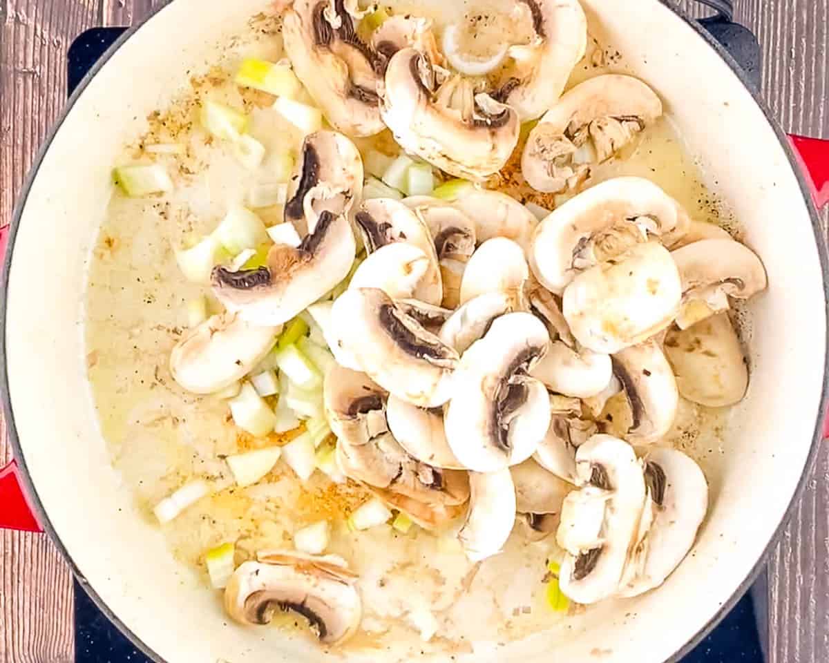 Sliced white mushrooms and diced onion in a cast iron skillet, just added to cook.