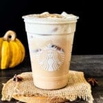 Iced pumpkin cream chai latte with pumpkin cold foam and a sprinkle of pumpkin pie spice in a reused Starbucks glass.