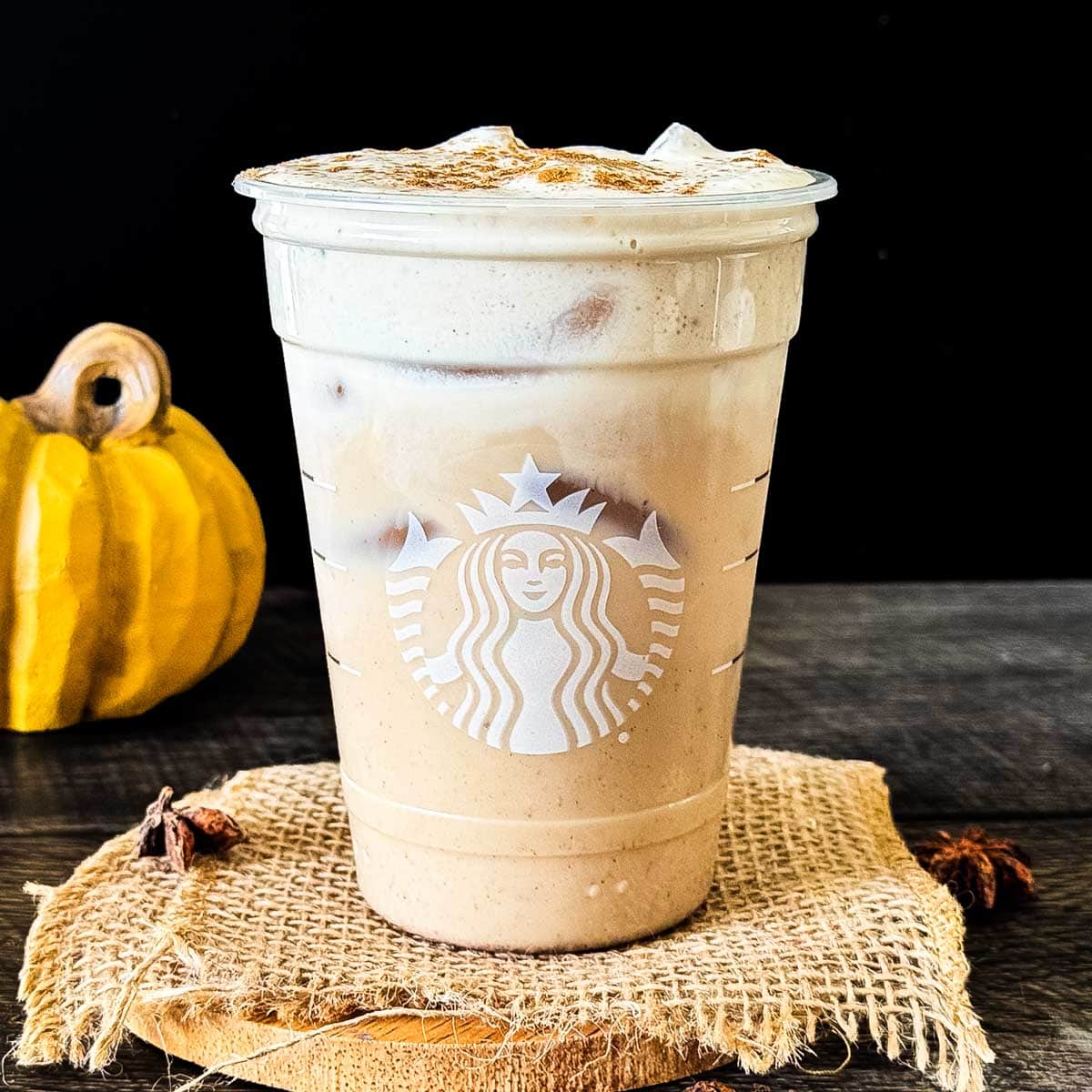 Iced pumpkin cream chai latte with pumpkin cold foam and a sprinkle of pumpkin pie spice in a reused Starbucks glass.