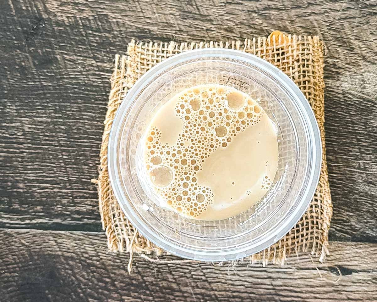Chai concentrate, milk, and pumpkin spice syrup stirred together in a clear cup.