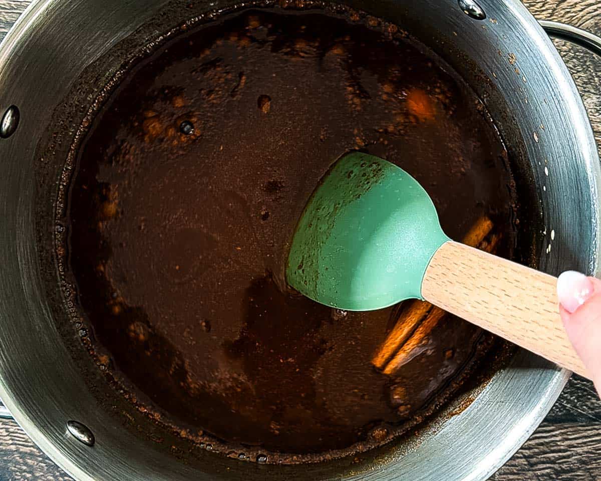 A spatula stirring pumpkin coffee syrup while it is simmering on the stove.