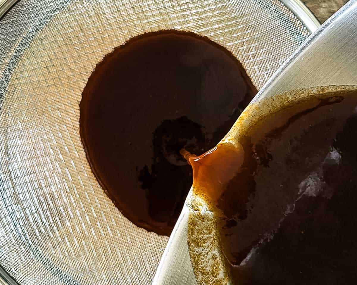 The pumpkin mixture being poured into a fine mesh strainer.