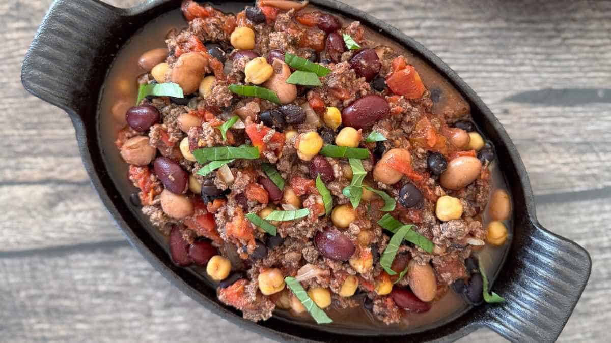 Smoked chili in a small cast iron dish, garnished with fresh herbs.