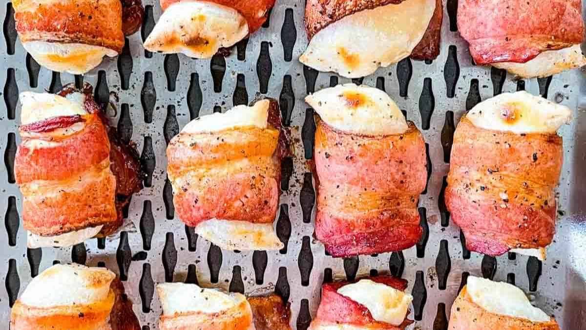Smoked perogies wrapped in bacon on a grilling tray.