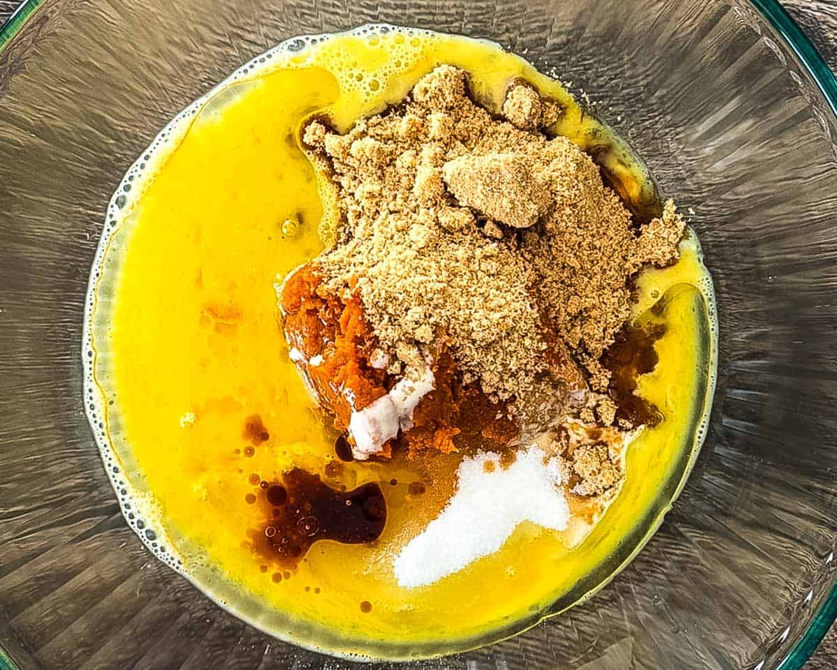 Pumpkin puree, sourdough discard, eggs, sugars, oil, and vanilla in a glass mixing bowl.